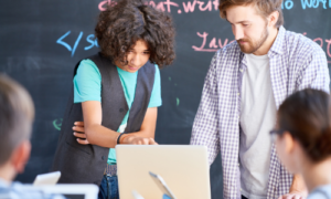 Student and teacher looking at laptop